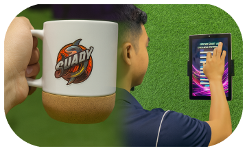 Two people customizing merchandise on tablets using Craft AI at an exhibition stand, with branded mugs and T-shirts displayed in a vibrant, professional setup